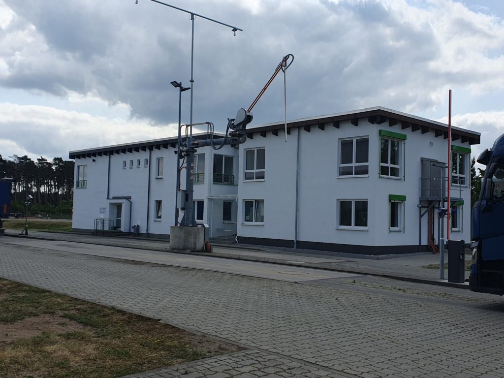 Moderne Verwaltungsgebäude mit Lkw-Zufahrt und technischen Einrichtungen in einem Industriegebiet.