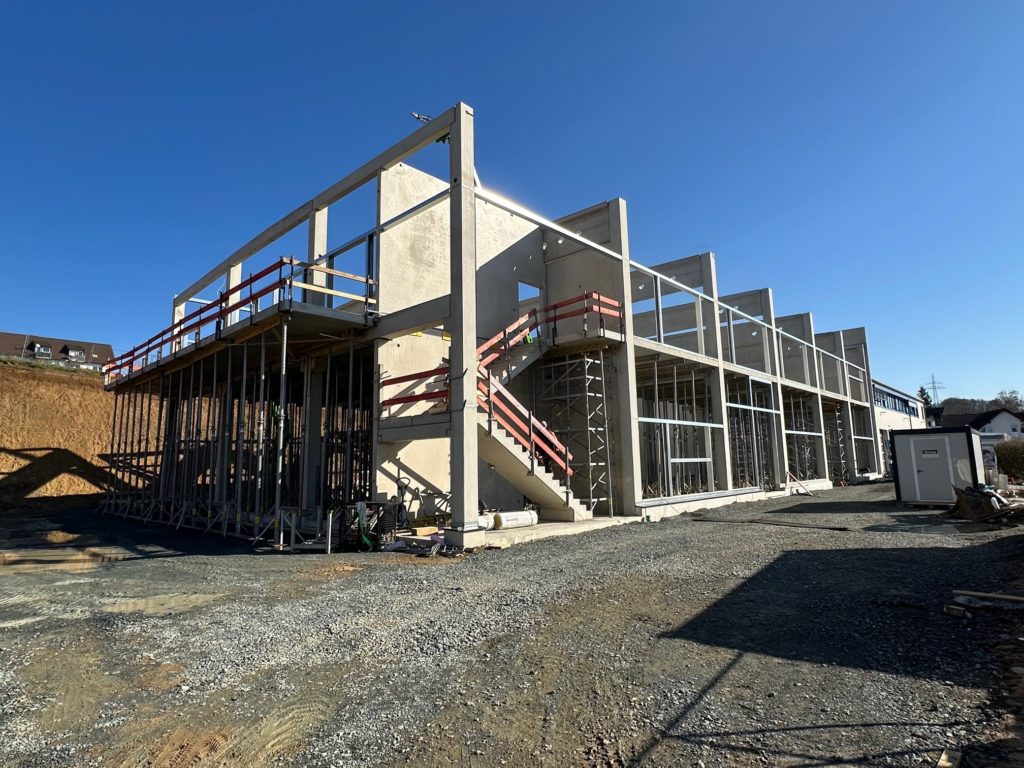 Unvollendetes Gebäude mit Betonstruktur, Gerüst und Treppe unter klarem Himmel.