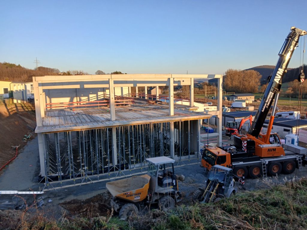 Bau einer modernen Struktur mit Kränen und Baufahrzeugen auf einer Baustelle im Freien.