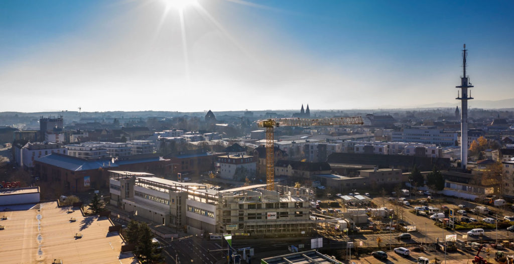 Blick auf eine Stadt mit Bauarbeiten, modernen Gebäuden und einer klaren blauen Himmelsszenerie.