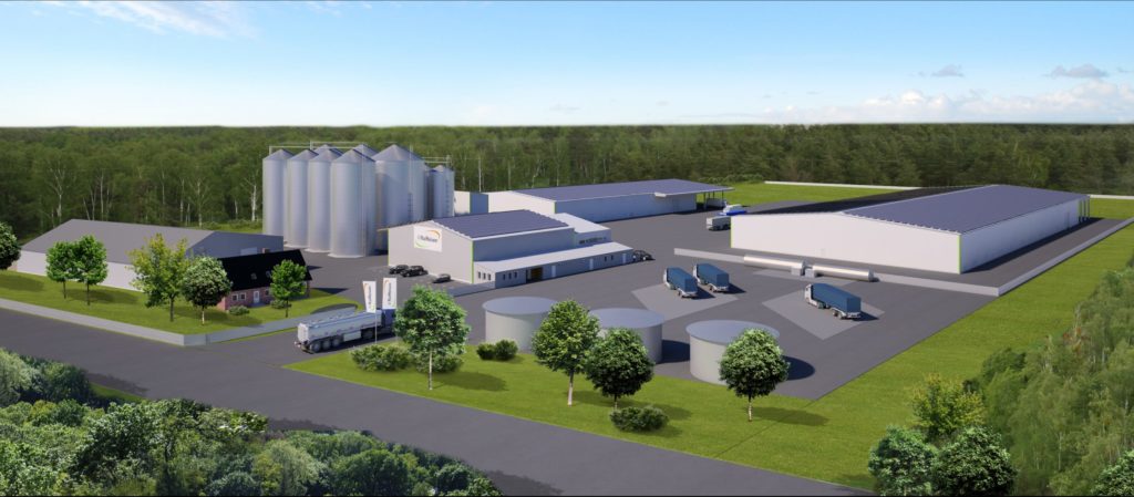 Moderne Lager- und Produktionsanlage mit Silos, Lkw und umliegenden Bäumen in ländlicher Umgebung.