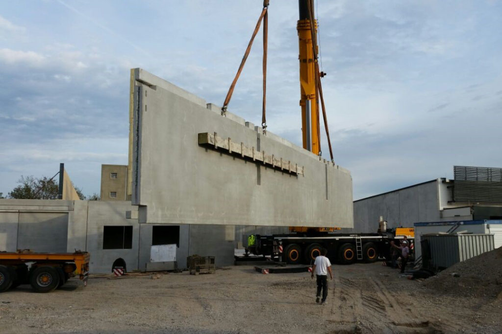 Ein Kran hebt eine große Betonschicht auf der Baustelle eines Einkaufszentrums in Stutensee-Blankenloch.
