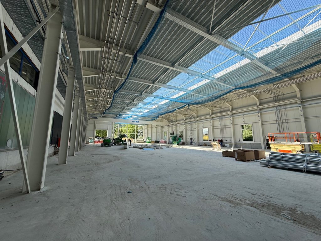 Großer, lichtdurchfluteter Innenraum eines Bauprojekts mit sichtbarem Rohbau und verschiedenen Materialien.