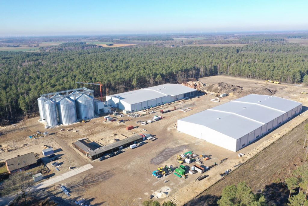 Luftaufnahme einer Lager- und Produktionsstätte mit Silos und Bauarbeiten in ländlicher Umgebung.