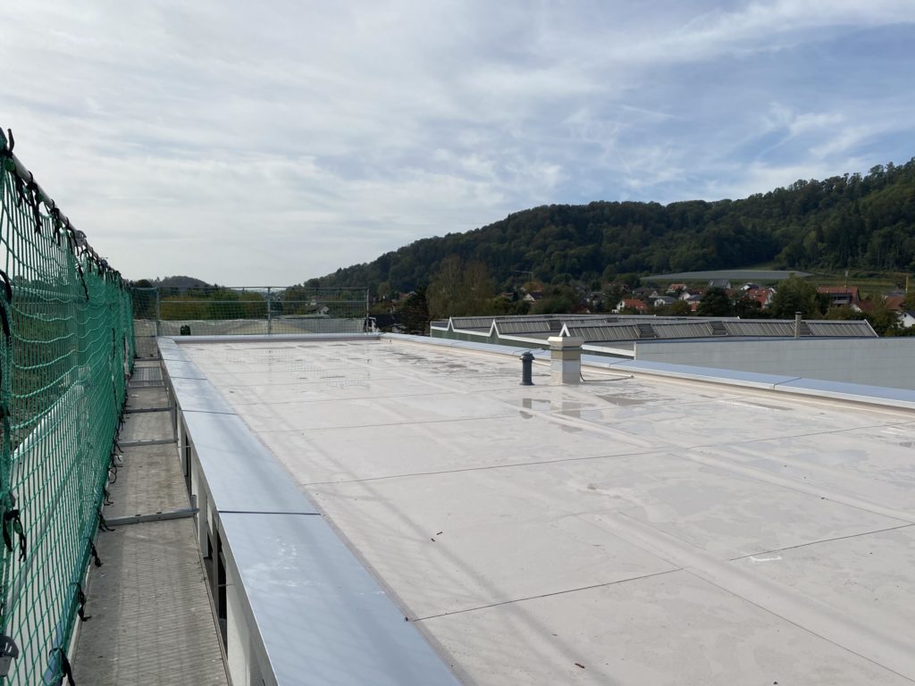 Blick auf ein flaches Dach mit Sicherheitsnetz und umliegender Landschaft, ideal für Bau- oder Renovierungsprojekte.